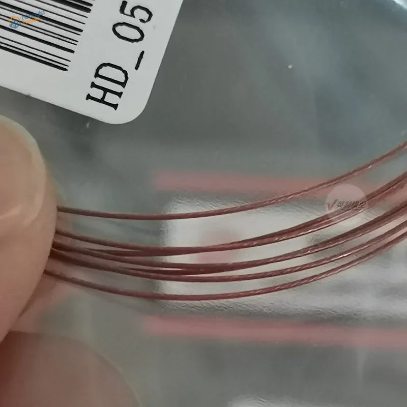 Hand holding red coppery 0.38mm colored steel wire strands with barcode label