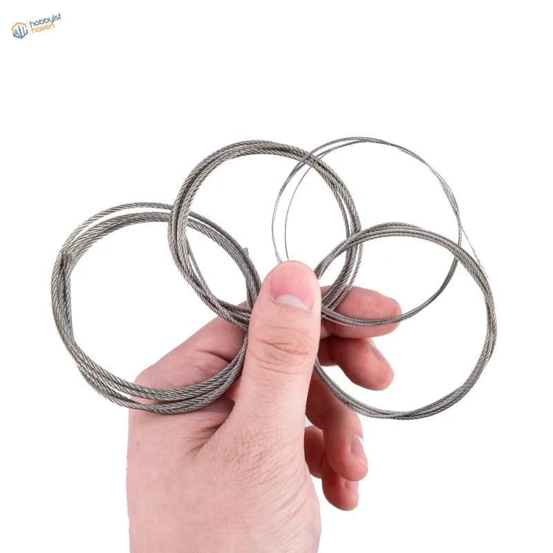 A hand holds coiled silver steel tow cable with braided texture for scale models and scale modeling tools