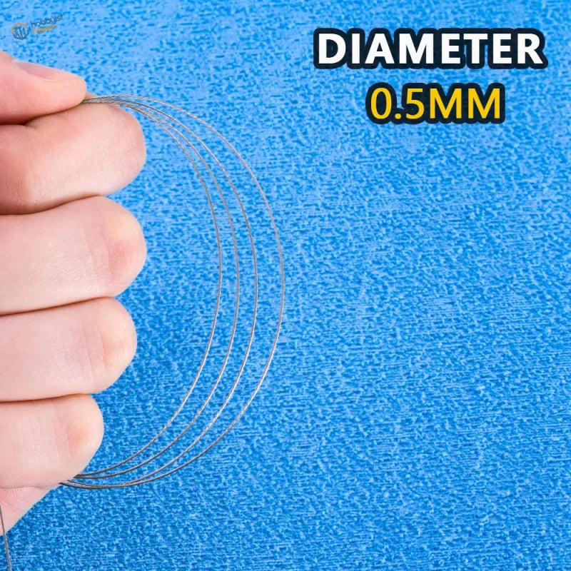 Thin 0.5mm metallic steel traction cable held in hand against blue textured background for model use