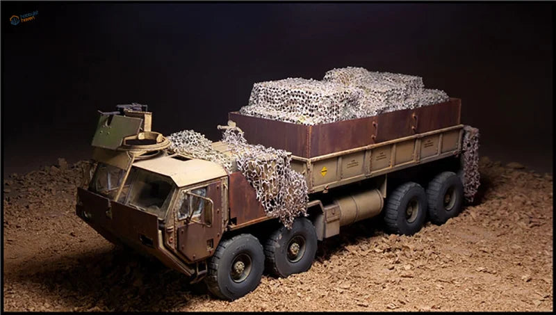 Detailed 1/35 brown military truck model with camouflage nets on dirt surface