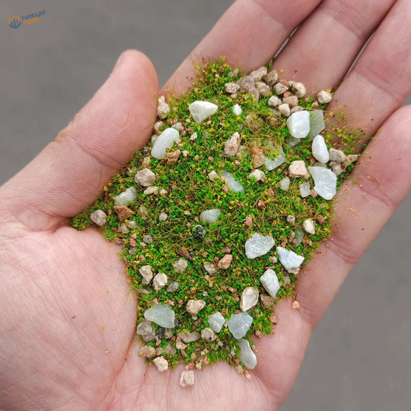 Hand holding 10/30g grass rocks for model making dioramas