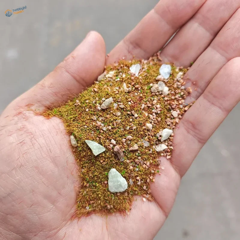 Hand holding 10/30g grass rocks for model making dioramas