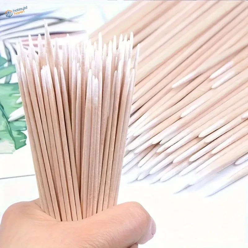 Hand holding bundle of light beige disposable micro cotton swabs with white tips