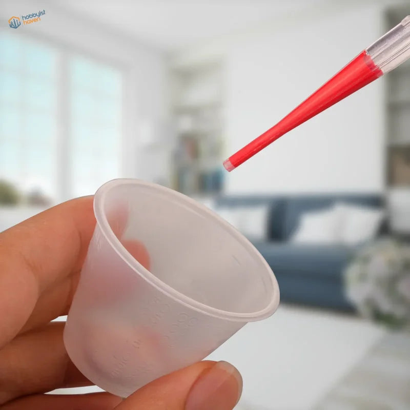 Hand holding 100pcs 30ml translucent mixing cup with red dropper, scale modeling tool
