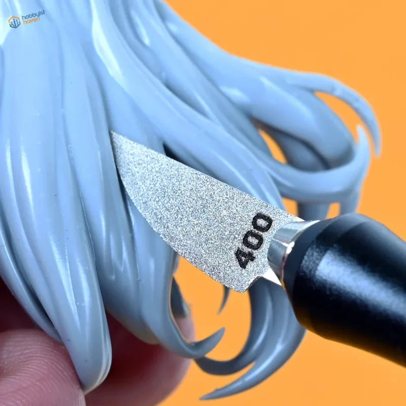 A silver 400-grit curved emery file blade with a black handle refining light blue plastic hair details