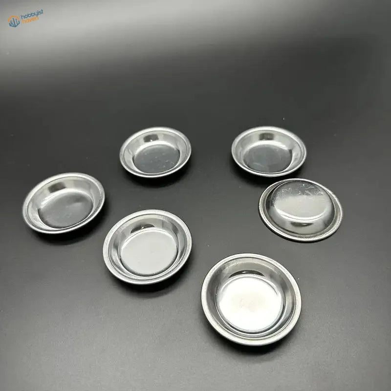 Six shiny 12pcs stainless steel pie pans on dark surface