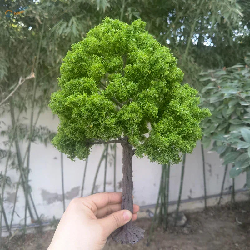 Hand holding 22-30cm artificial tree for scale modeling with mossy green foliage