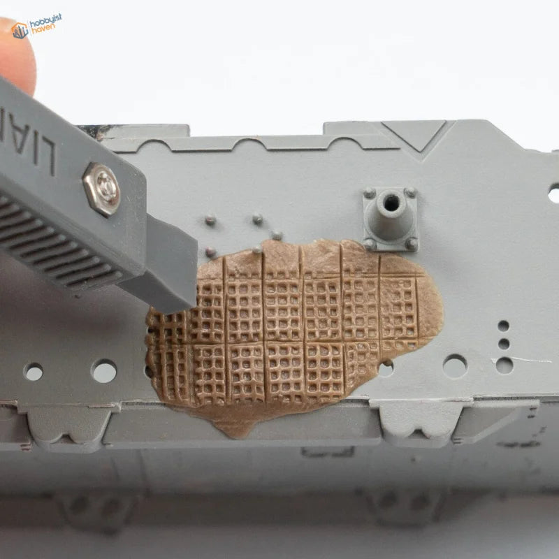 3D printed tool applies brown waffle-patterned piece to gray chassis for Zimmerit modeling