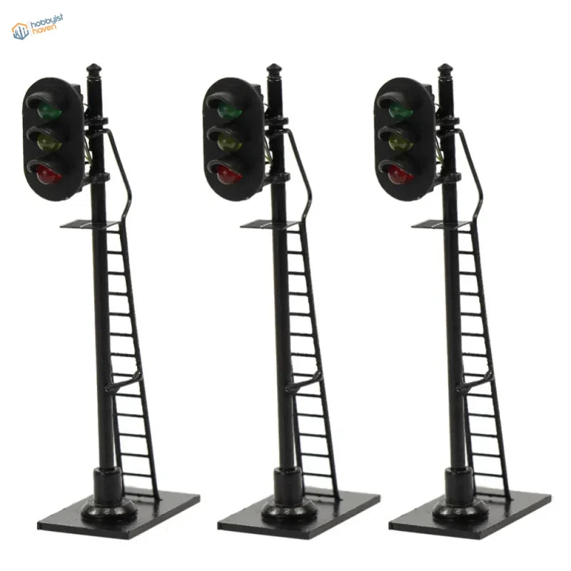 Three black ho scale railway block signals with red and green lights on poles with attached ladders