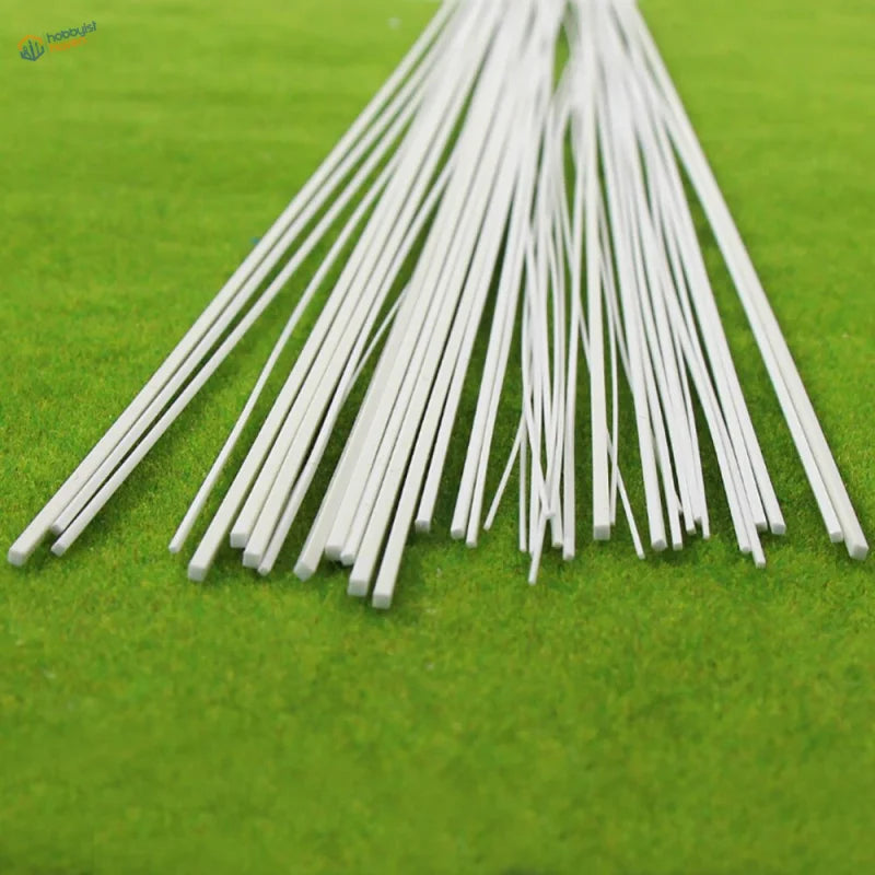 40pcs styrene square rods in fan-like pattern on green surface for scratch builds