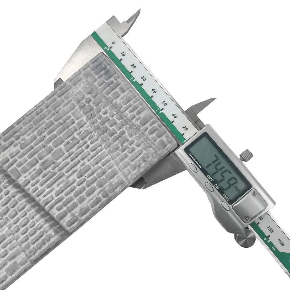 Silver digital caliper measuring gray metallic n scale stone retaining wall with textured embossed brick pattern