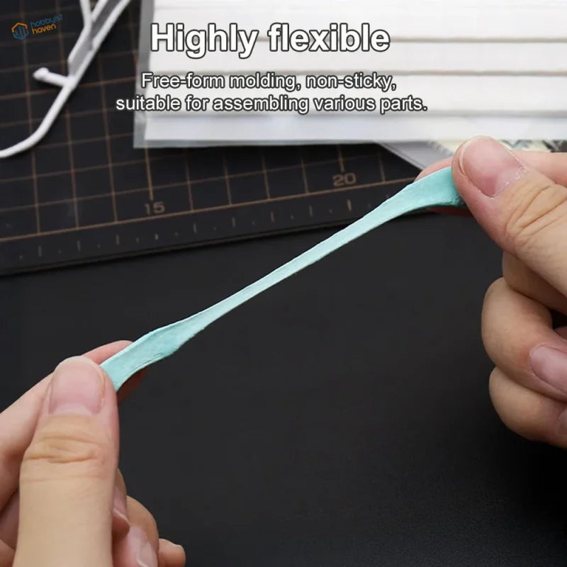Light blue reusable tack stretched between fingers for scale modeling