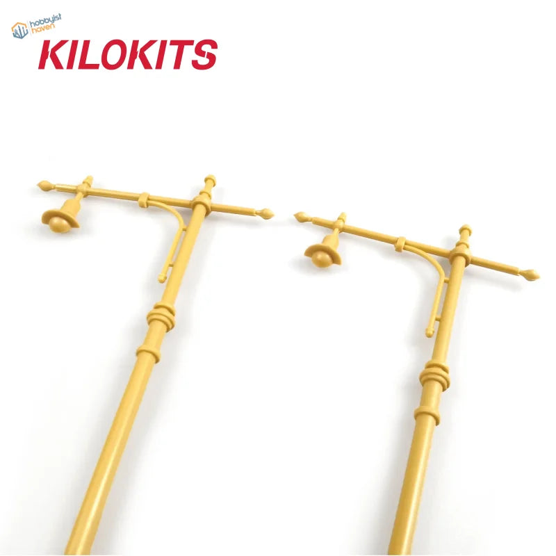 Two yellow plastic 1/35 scale street lamps with crossarms and bell-shaped light fixtures for model building tools