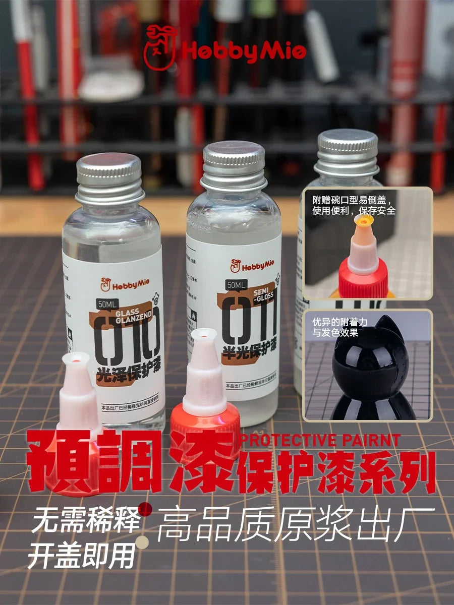 Three clear glass bottles with silver caps containing hobbymie hobby mio 50ml pre-mixed varnishes for precision hobby tools