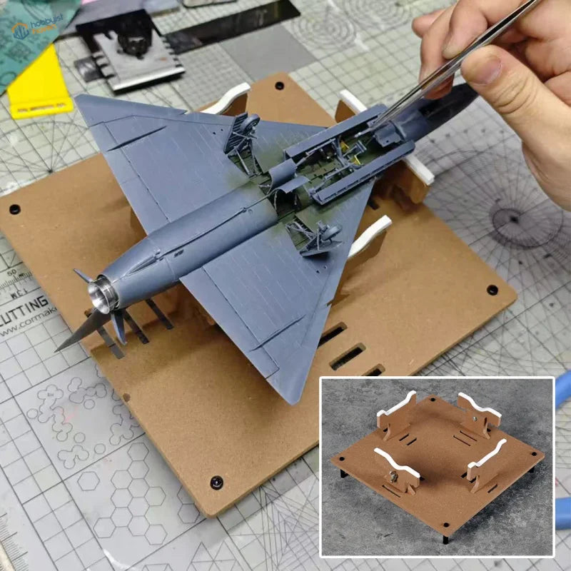 Adjustable aircraft model painting stand holding a gray plastic model airplane with metallic nose cone for precision hobby tools