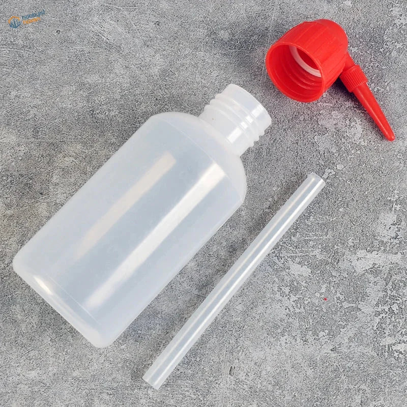 Airbrush cleaning bottle with clear plastic body, red cap, nozzle and straw