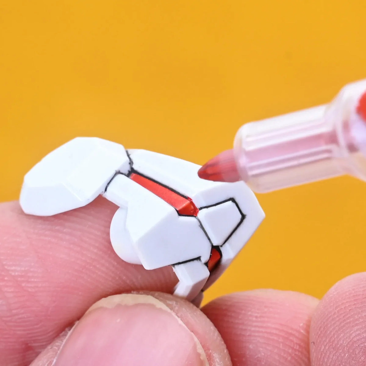 White plastic gundam model part detailed with red accents using lazy master metallic paint markers for precision coloring