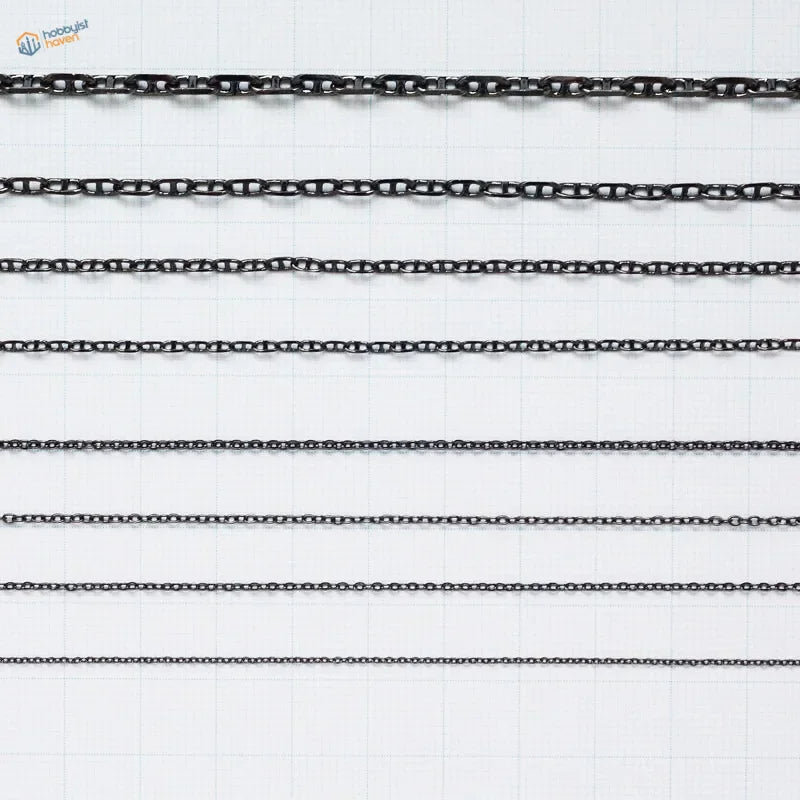 Black metal anchor chains with varying link styles arranged in parallel rows for model ships use