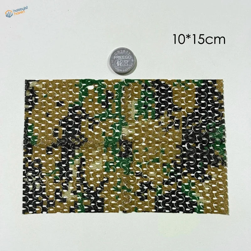 A rectangular piece of camouflage netting fabric with green black and tan woven design for flexible cloth train layouts
