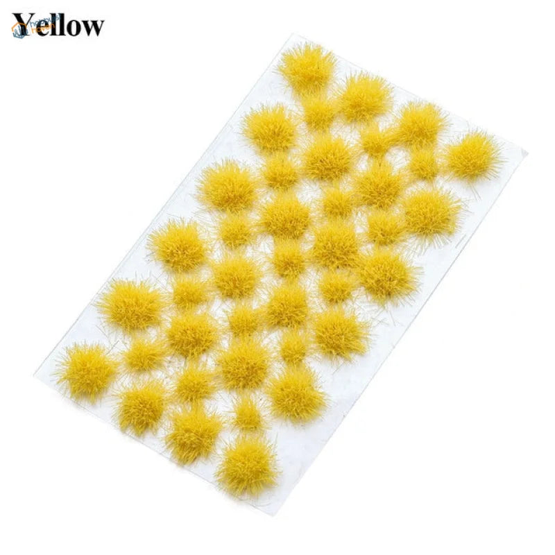 Yellow fuzzy pom-poms as grass flower patches on clear plastic sheet