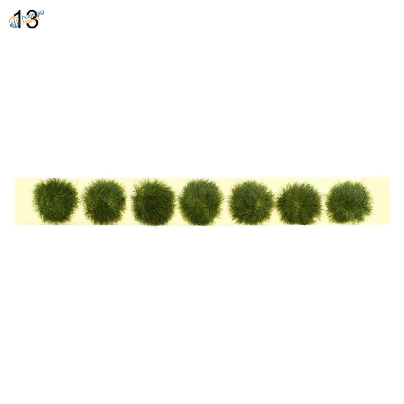 Six artificial green grass tufts on pale yellow strip for grass flower patches