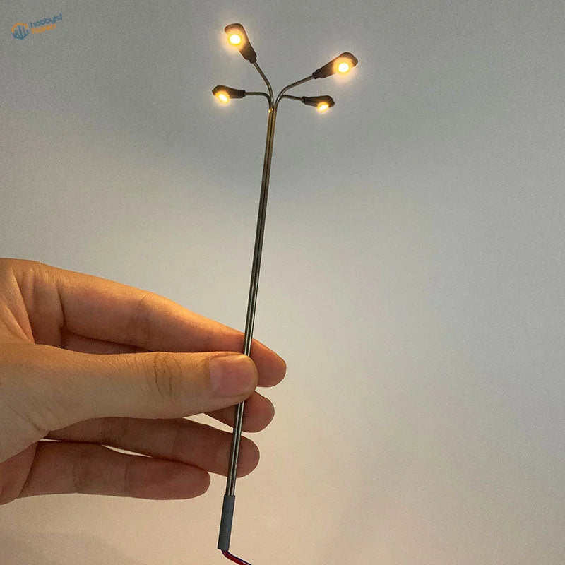 Ho scale LED street lamp with four glowing amber lights on slender pole