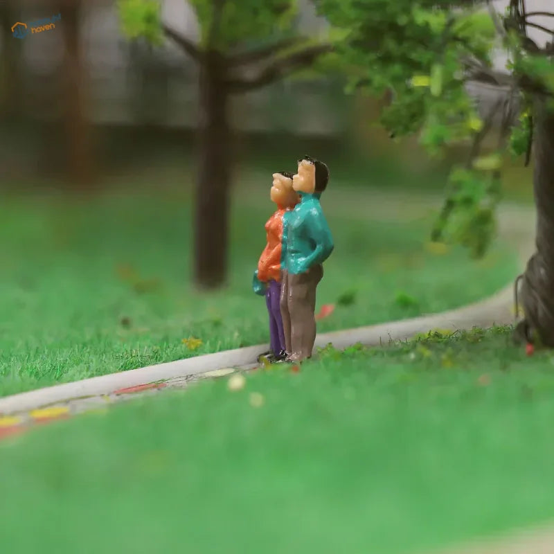 HO scale people figures set: orange-purple and teal-brown miniatures on grass path