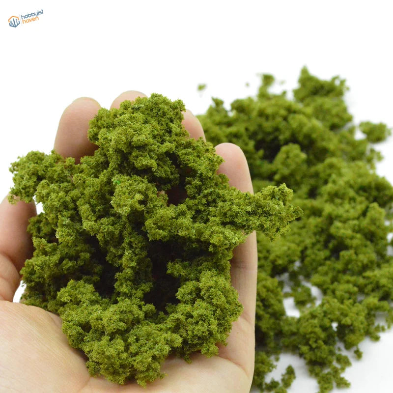 Hand holding vibrant green HO scale tree powder moss for railroad scenery