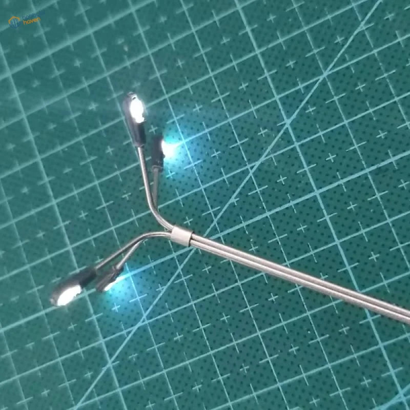 A sleek silver scale led street lamp model with three glowing led bulbs and a curved metallic arm for HO/TT scale