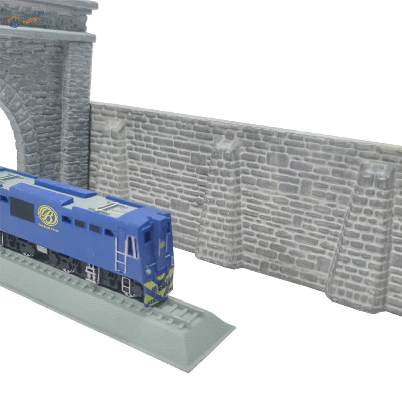Blue model train engine with yellow and black accents beside n scale stone retaining wall and viaduct retaining wall