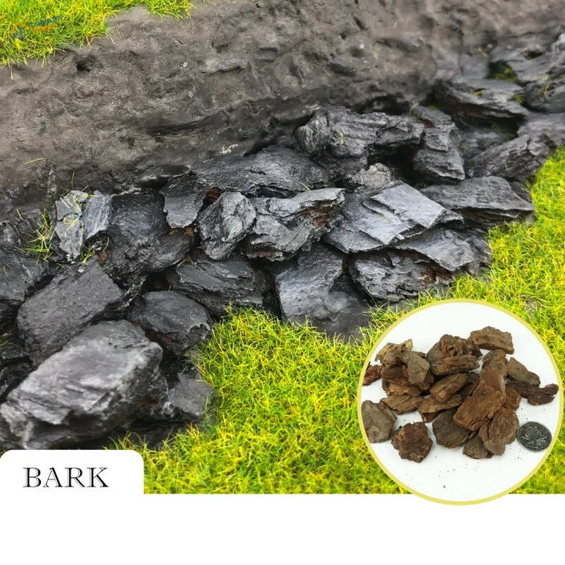 Pile of dark rough tree bark for scale modeling dioramas on green grass