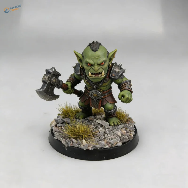 Green-skinned orc miniature with orange eyes on scenic base toppers featuring gravel and grass for scale modeling tools