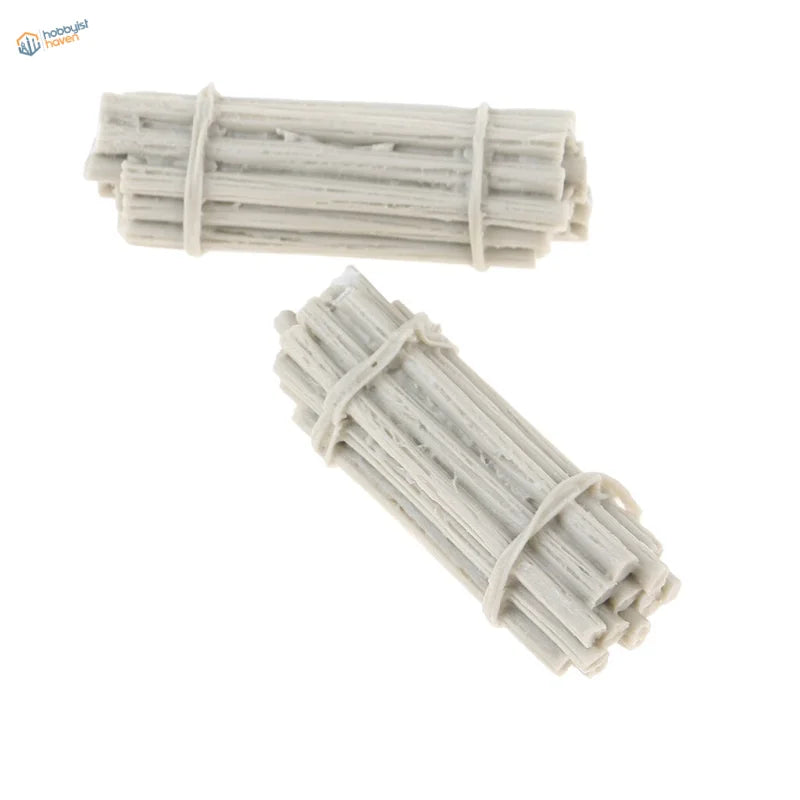 Two off-white, miniature bundles of sticks tied together with thin straps.