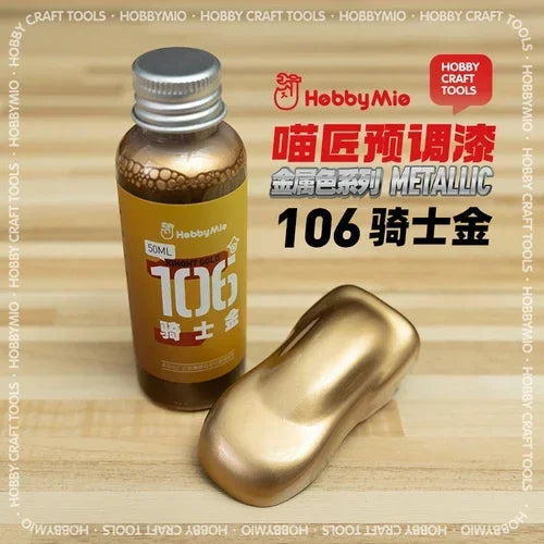 A bottle of hobby mio 50ml oil-based metallic gold paint with silver cap and golden applicator for precision hobby tools