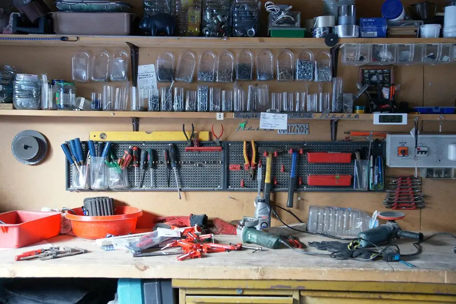 Green and black cordless drill resting on cluttered workbench highlighting need for neat work environment storage units