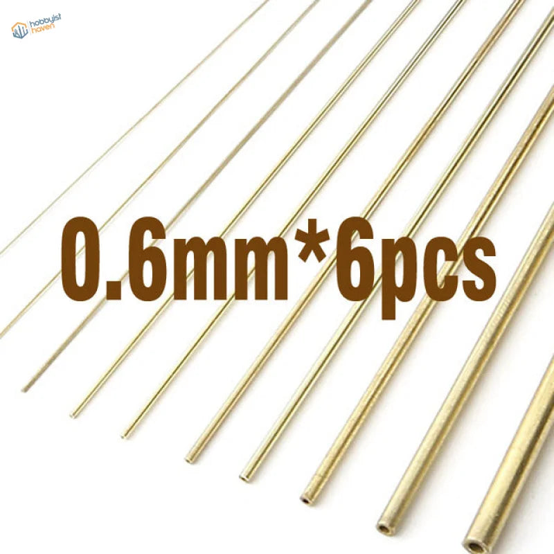 Six 0.6mm brass tubes for scale modeling, diagonal on white background