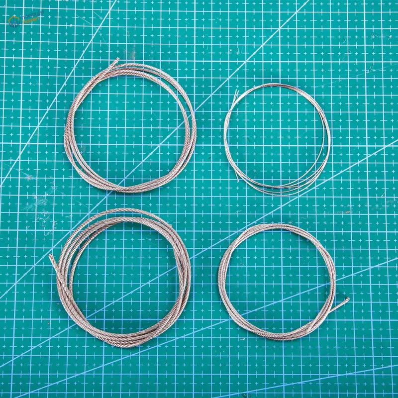 Four coiled stainless steel traction cables with braided texture and metallic sheen for 0.5 to 2mm steel traction cable models