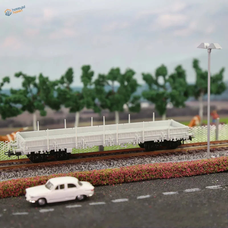 White plastic 1/87 HO scale flat car model on miniature railway track for use with scale modeling tools and model building tools