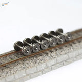 A set of six 1/87 HO scale metal train wheels with metallic silver finish and detailed axles on miniature railway track