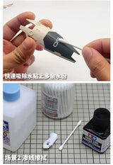 Cotton swab removing adhesive residue from black beige model airplane part
