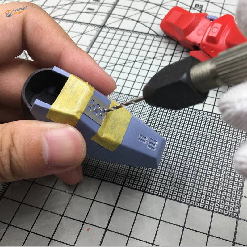 Blue Gundam model part with yellow tape for panel lines carving template drilling