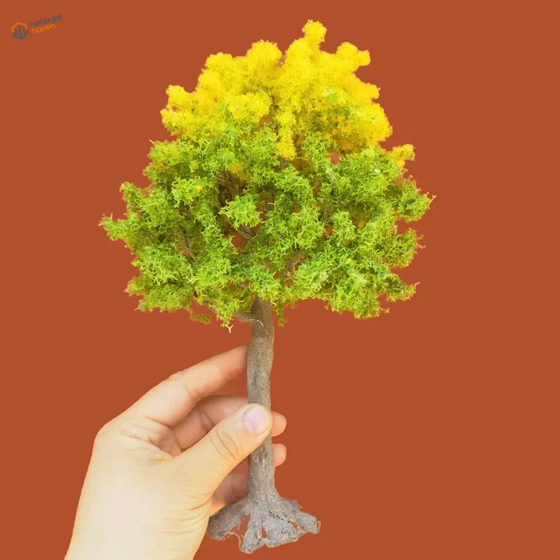 Hand holding 22-30cm artificial tree for scale modeling with mossy crown