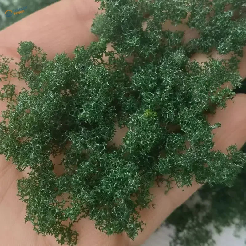 Hand holding 22g Green Tree Powder moss for scale modeling tools
