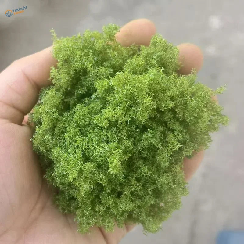Hand holding 22g Green Tree Powder vibrant fluffy green mossy cluster for scale modeling tools