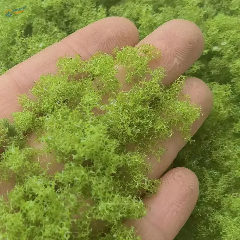 Hand holding 22g Green Tree Powder, vibrant fluffy moss for scale modeling tools