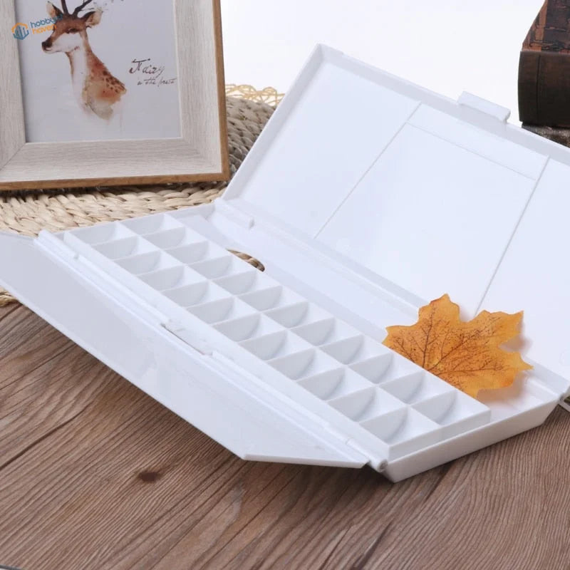 24 grid watercolor paint palette with dried orange maple leaf