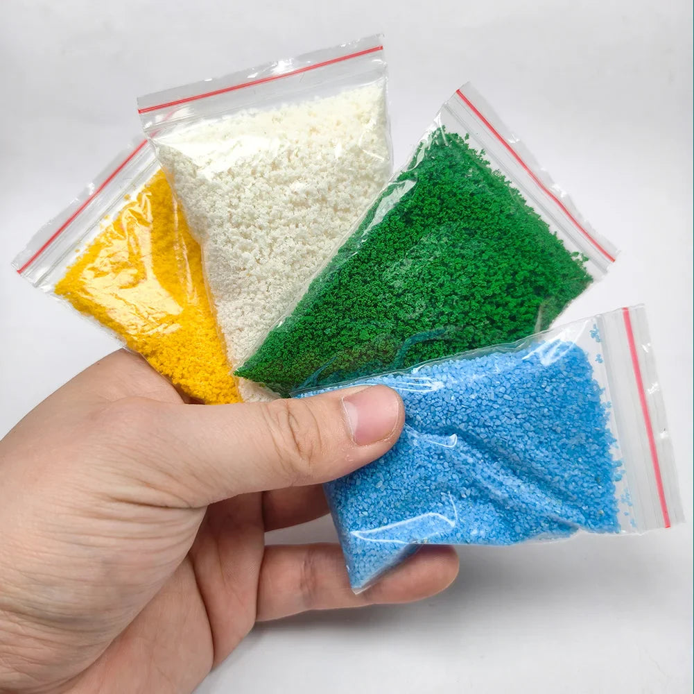 Four clear plastic bags with colored granular crushed coal in a nine-piece scenery starter pack for diorama scenery