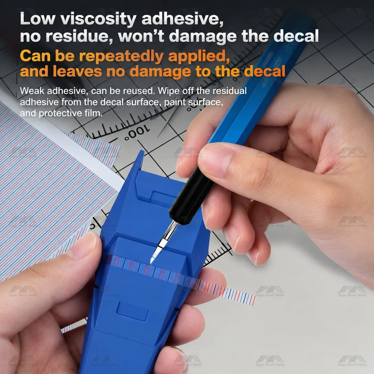 Hand holding a scriber against scribing tape on a blue model part with a decal underneath
