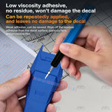 Hand holding a scriber against scribing tape on a blue model part with a decal underneath