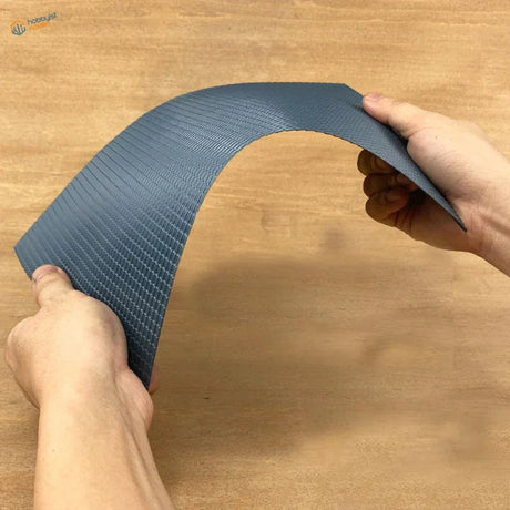Hands bending flexible dark gray roof simulating PVC panel woven texture